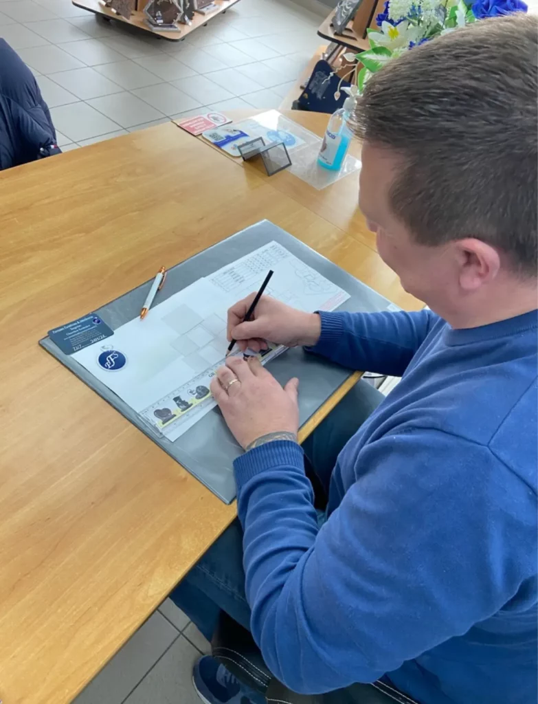 Un professionnel dessine les plans d'un monument funéraire à son bureau.