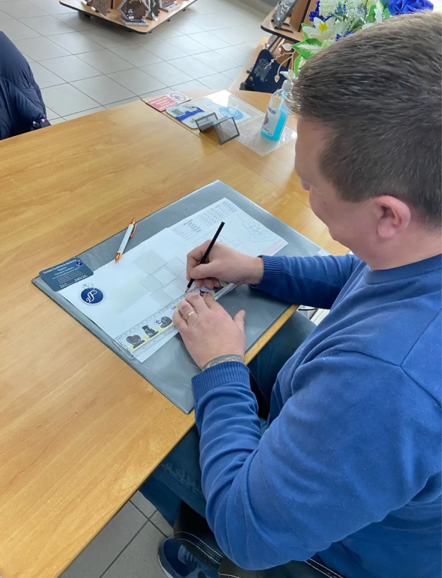 Un professionnel dessine les plans d'un monument funéraire à son bureau.