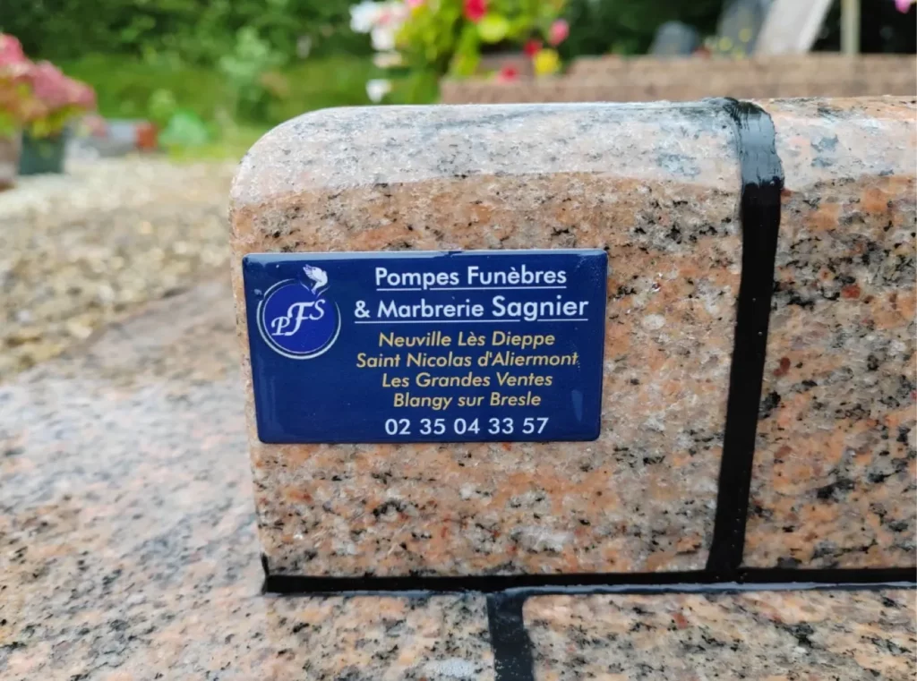 Détail d'une plaque d'identification Pompes Funèbres Sagnier sur granit rose.