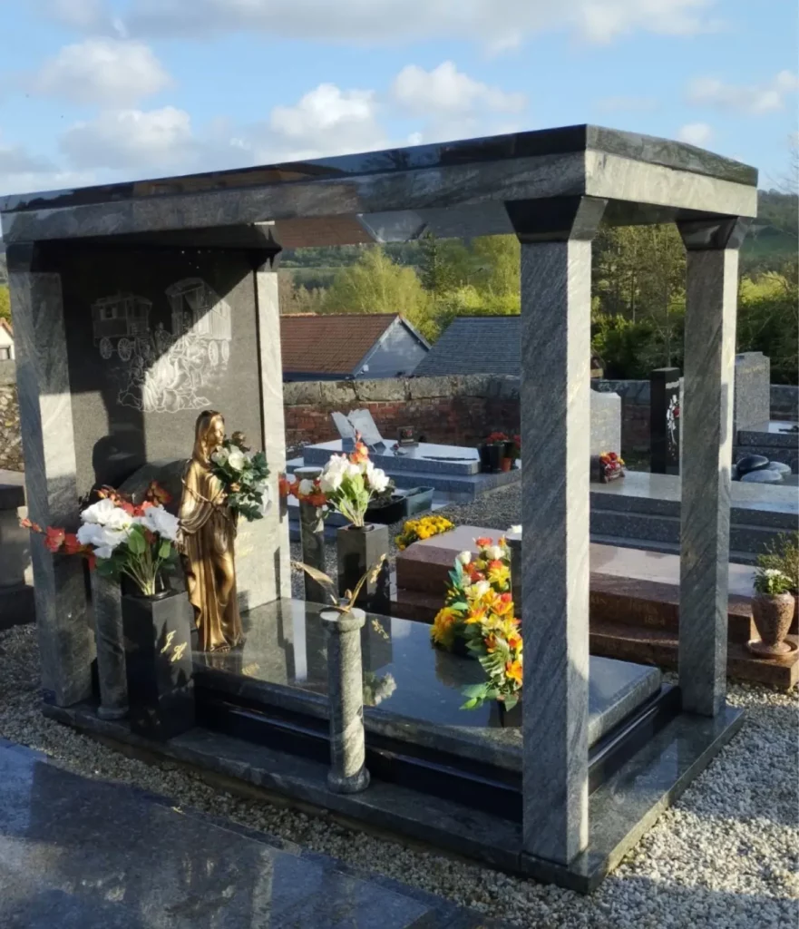 Chapelle funéraire ouverte en granit avec colonnes, stèle gravée et statue de la Vierge Marie.