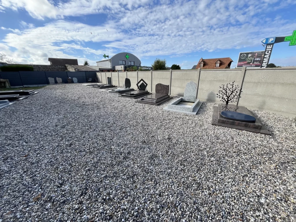 Alignement de stèles et monuments funéraires exposés sur un espace recouvert de graviers.