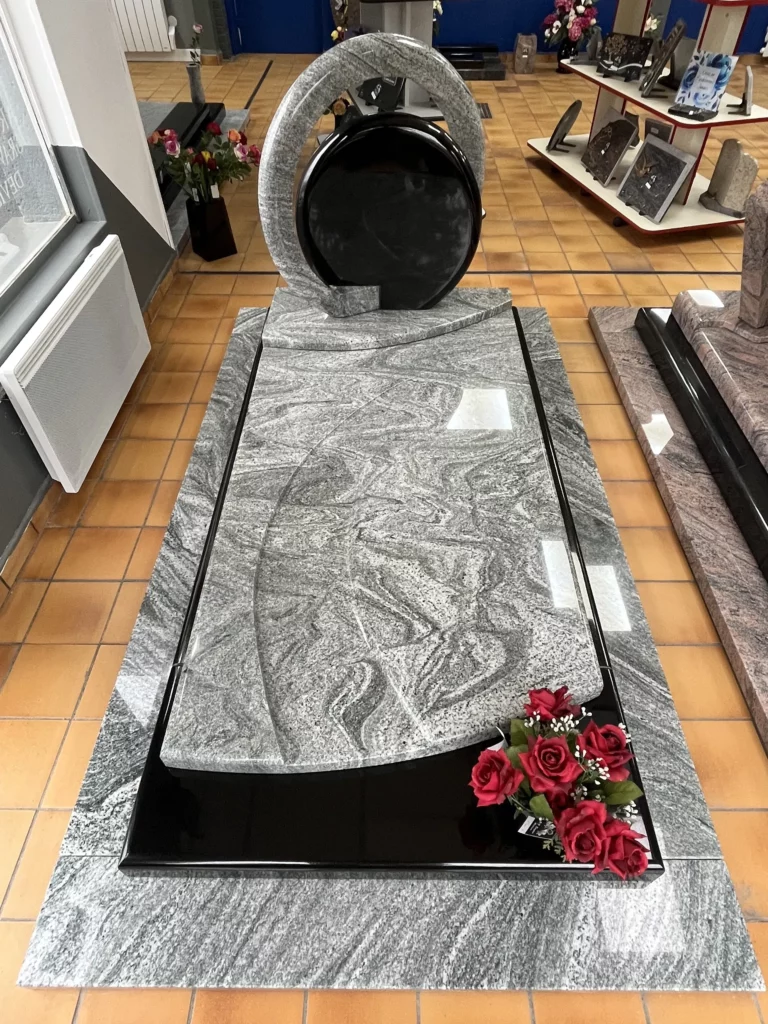 Modèle de monument funéraire design en granit gris veiné et noir avec stèle circulaire en exposition.