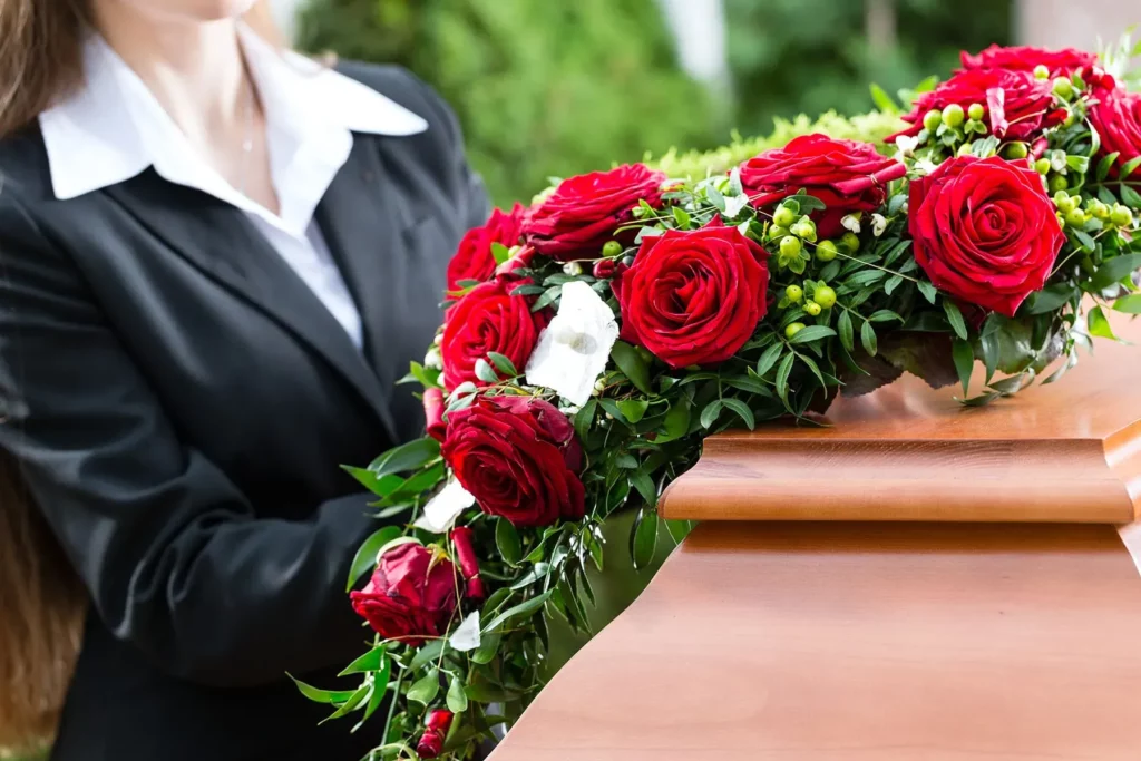 Coussin de deuil de roses rouges sur un cercueil en bois lors d'obsèques