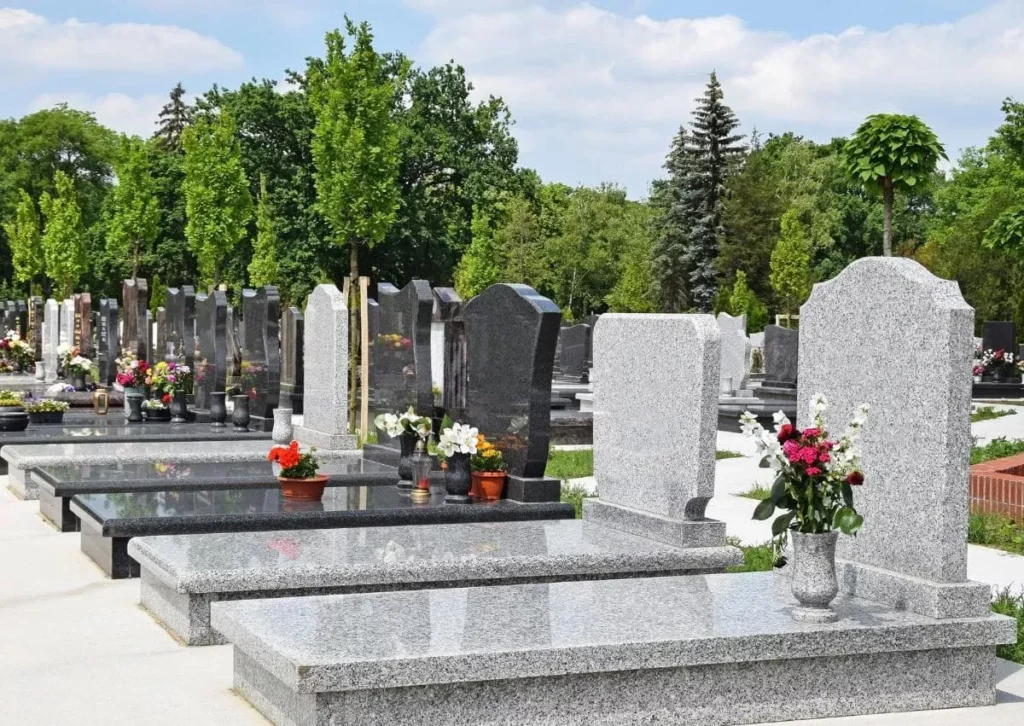 Alignement de monuments funéraires en granit gris et noir dans un cimetière.